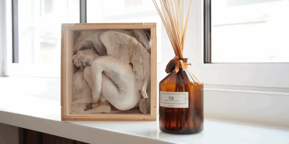 An angel sculpture in relief next to a Magna Pars fragrance diffuser